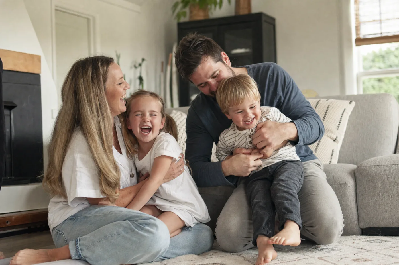 Candid family lifestyle moment at home, parents and kids laughing together on the couch